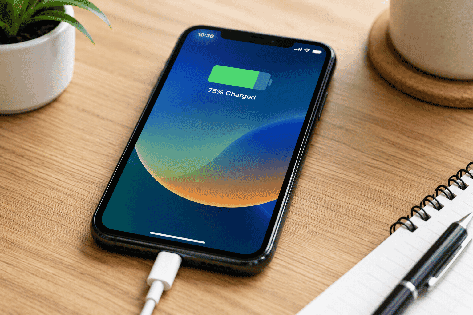 Smartphone connected to a charging cable on a desk.