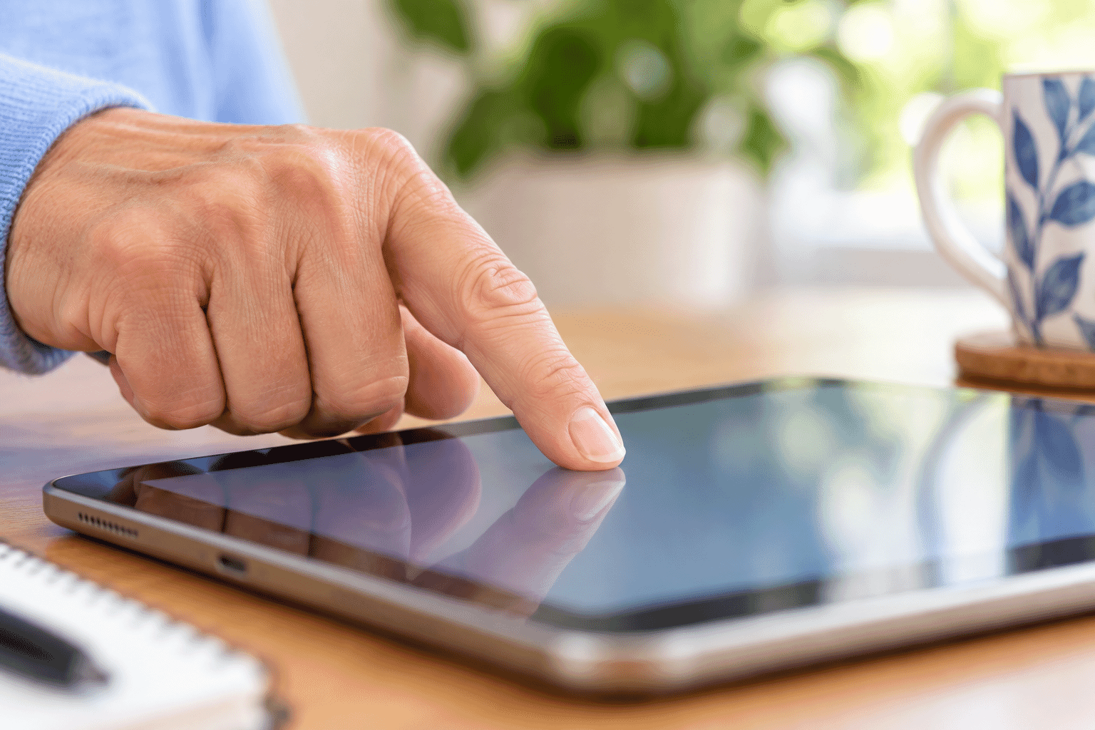 Fingertip lightly touching a tablet screen without pressing firmly.